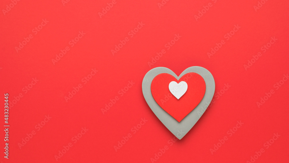 Three wooden hearts lying in a pile on a red background. The concept of falling in love and Valentine's day. Minimalism. Three wooden hearts lying in a pile on a red background. The concept of falling in love and Valentine's day. Minimalism.