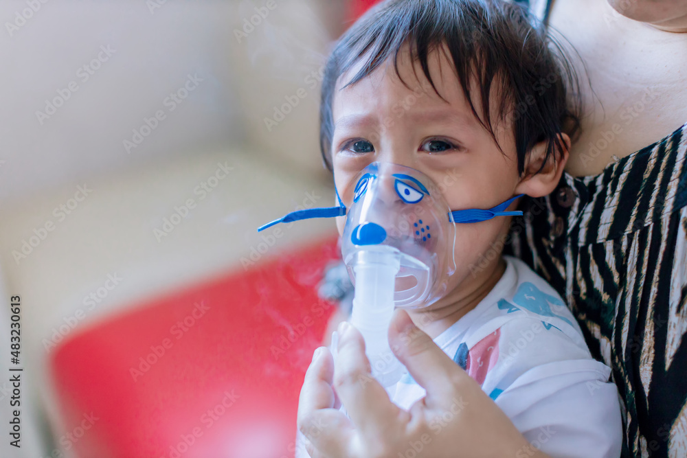 Sick boy inhalation therapy by the mask of inhaler. Baby has asthma and ...