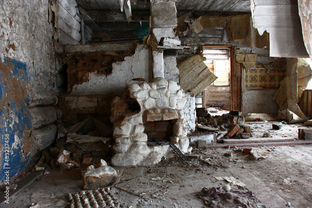 The abandoned wooden rural house. Garbage, the torn-off wall-paper, a dirty ceiling. Near the furnace there is an original fireplace from a stone in white color.