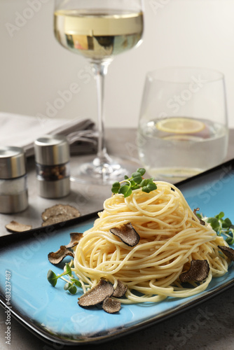 Delicious pasta with truffle slices and microgreens served on light grey table