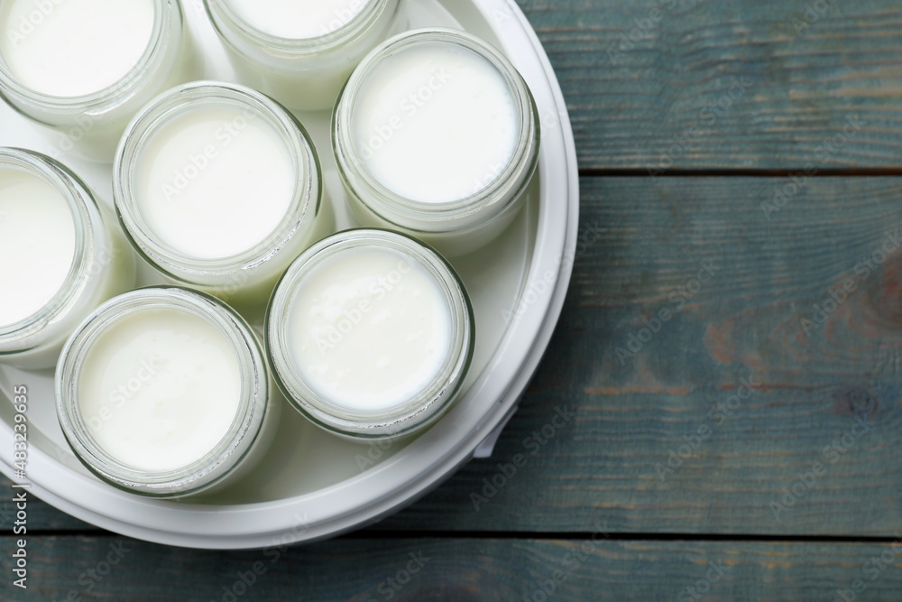 Modern yogurt maker with full jars on blue wooden table, top view. Space for text Modern yogurt maker with full jars on blue wooden table, top view. Space for text