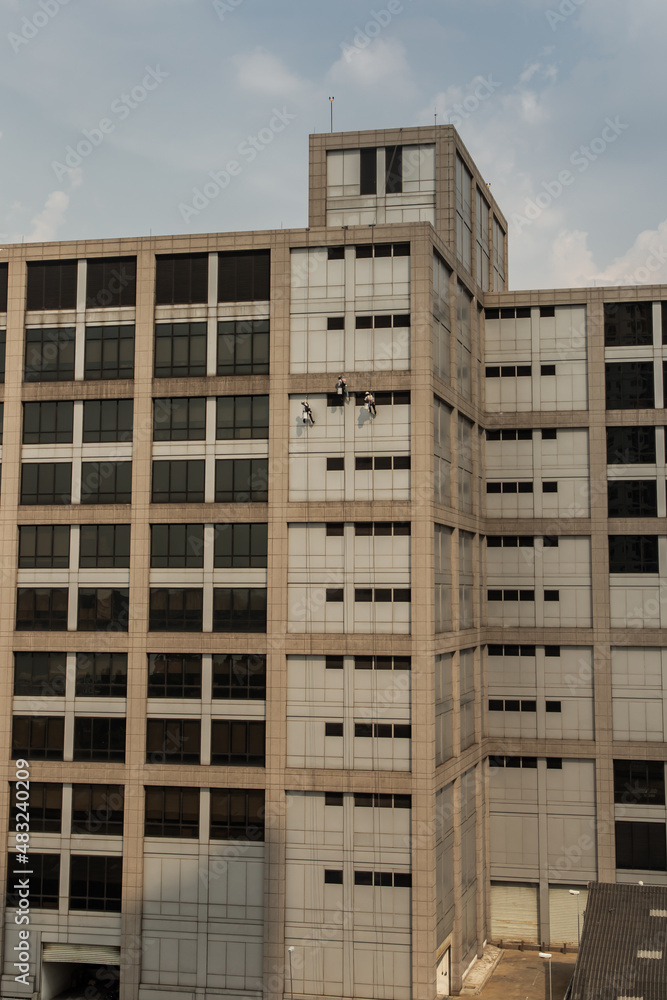 Group of workers cleaning windows service on high rise office building with reflection from swimming pool. Selective focus.