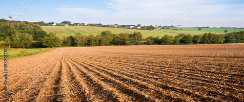 panorama of spring plowed fields and a village on the horizon