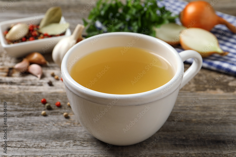Hot delicious bouillon in cup on wooden table, closeup Hot delicious bouillon in cup on wooden table, closeup