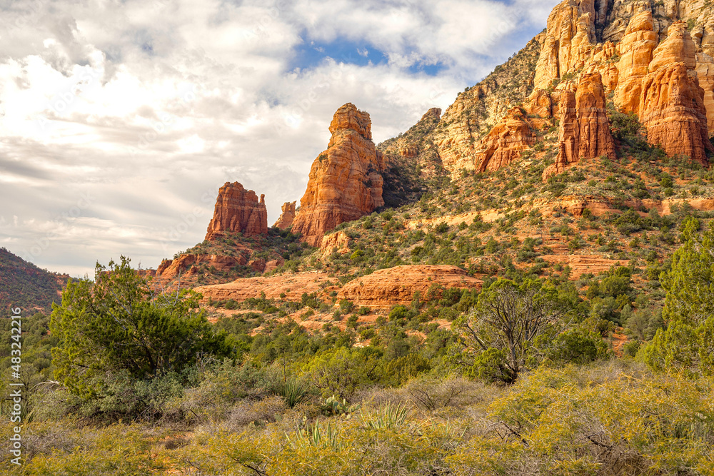 The red rock formations reaching for the sky as the sun warms the stone and highlights the autumn leaves is a typical scenic landscape in the spiritual, beautiful Sedona, Arizona in western USA The red rock formations reaching for the sky as the sun warms the stone and highlights the autumn leaves is a typical scenic landscape in the spiritual, beautiful Sedona, Arizona in western USA