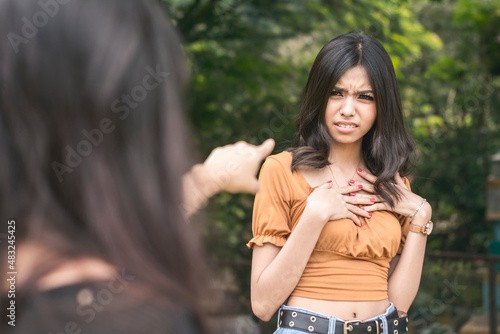 A young asian woman is insulted by accusations hurled on her by another girl. Standoff at a park.