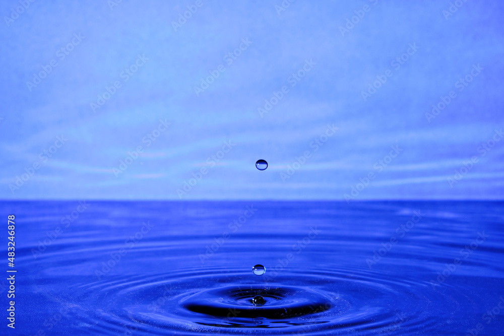Splash water after drop falls.Lilac abstract background with drop in water. Splash water after drop falls.Lilac abstract background with drop in water.