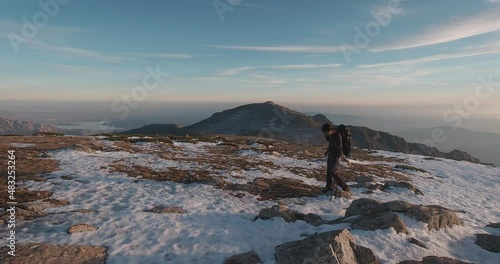 Side view of Young hiker with backpack and trekking poles in snowy Guadarrama mountains, Madrid, Spain. photo