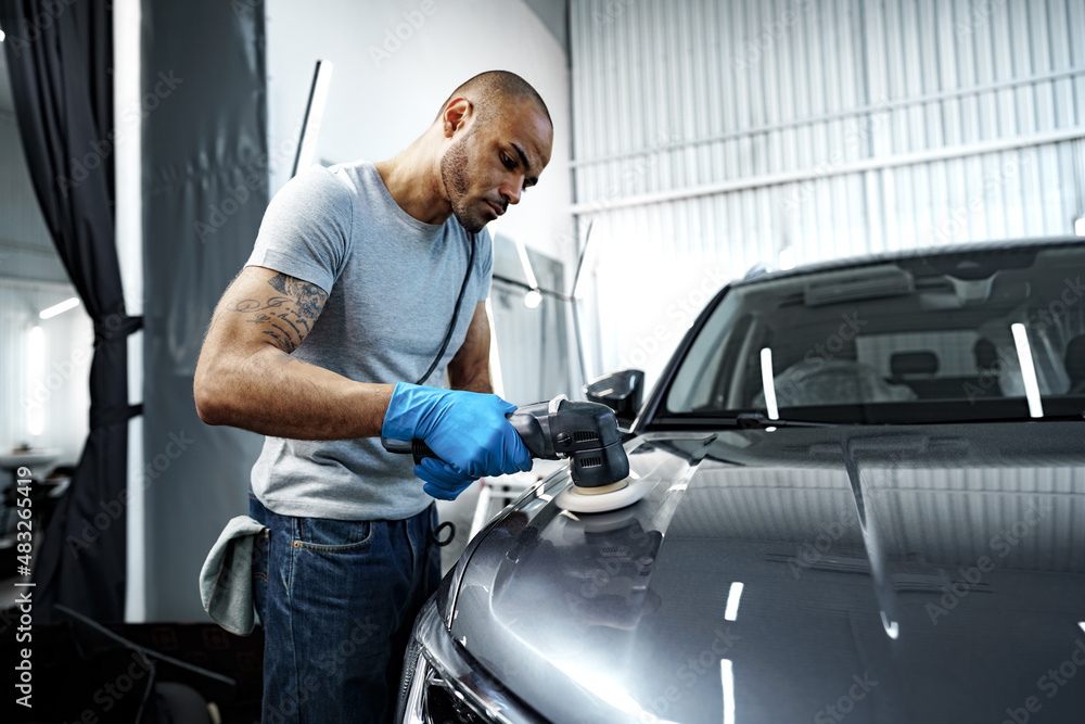 Car detailing. Male hands with orbital polisher in auto repair shop Car detailing. Male hands with orbital polisher in auto repair shop