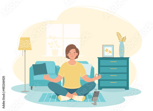 Young woman is sitting in lotus position and meditating. Aerobics, fitness or yoga classes at home. Concept of online training. © Olga
