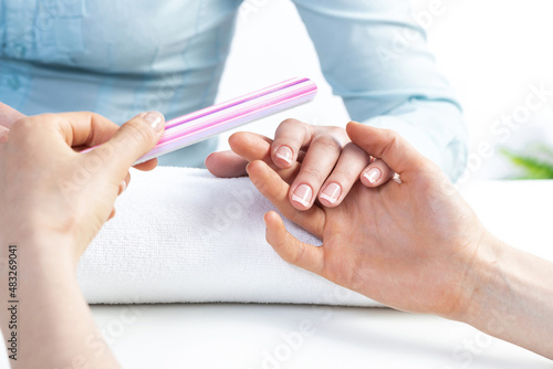 Manicurist using nail file and create clean shape