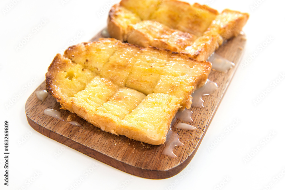 Bread toast and condensed milk on wooden plate Bread toast and condensed milk on wooden plate