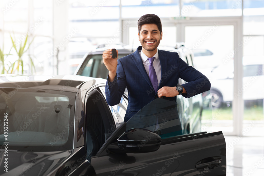 Middle-eastern businessman showing car key and smiling Middle-eastern businessman showing car key and smiling