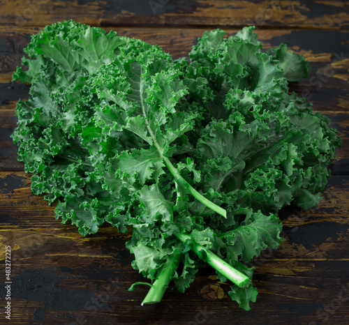 Curly kale  on a brown wooden table, top view