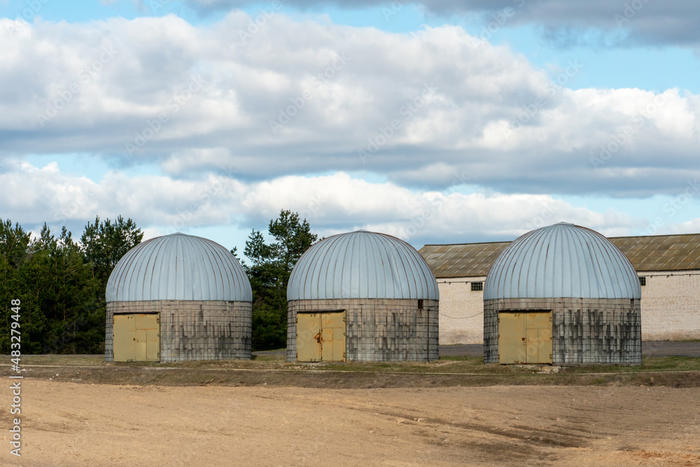 silver silos on agro manufacturing plant for processing drying cleaning and storage of agricultural products, flour, cereals and grain. an old warehouse on a farm with a round roof silver silos on agro manufacturing plant for processing drying cleaning and storage of agricultural products, flour, cereals and grain. an old warehouse on a farm with a round roof