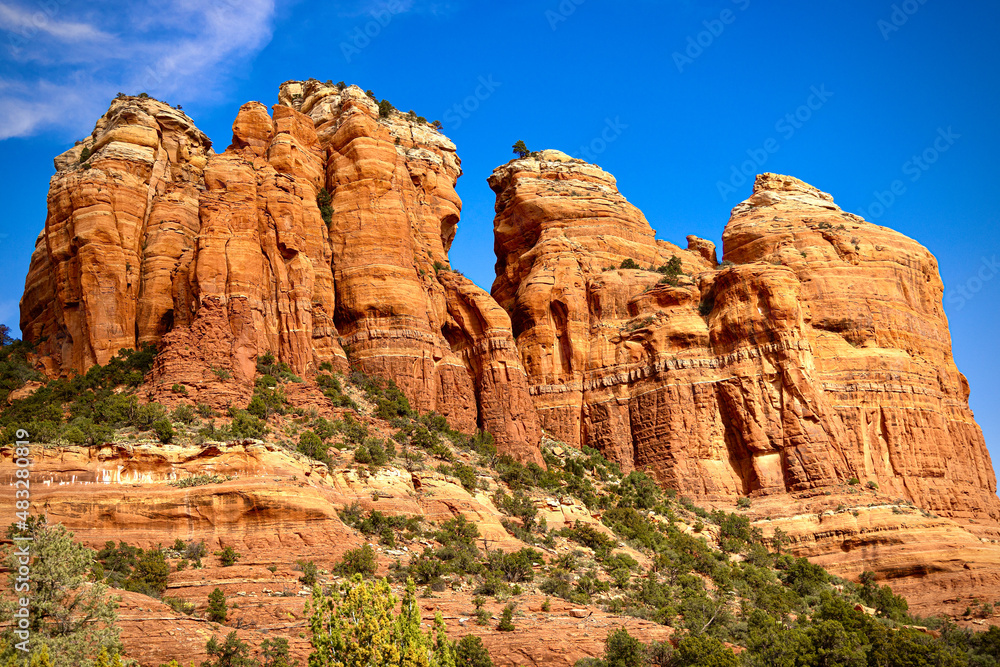 Large orange red rock formations and vistas of desert plants leading to mountains and valleys in Sedona, Arizona adds to the beauty of the wilderness