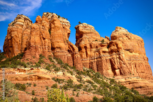 Large orange red rock formations and vistas of desert plants leading to mountains and valleys in Sedona, Arizona adds to the beauty of the wilderness