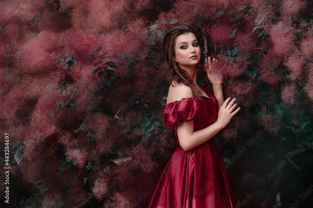 Beautiful woman in red dress walking in the garden full of roses. Beautiful woman in red dress walking in the garden full of roses.