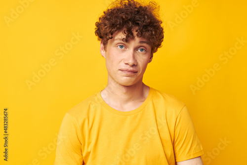 portrait of a young curly man Youth style glasses studio casual wear yellow background unaltered
