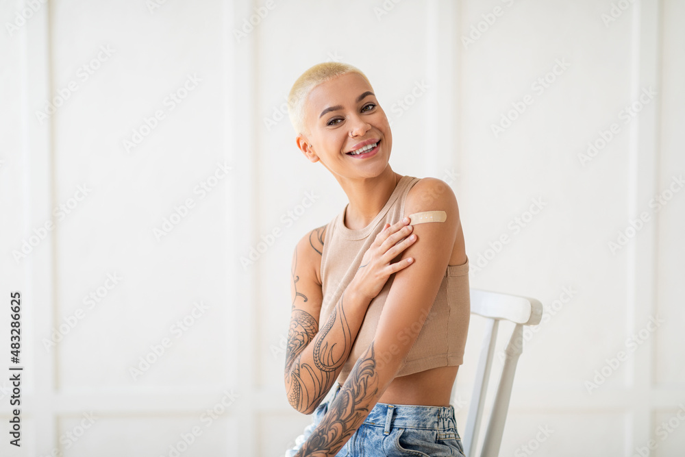 Happy vaccinated lady showing arm with medical bandage after coronavirus antiviral vaccine injection, smiling at camera Happy vaccinated lady showing arm with medical bandage after coronavirus antiviral vaccine injection, smiling at camera