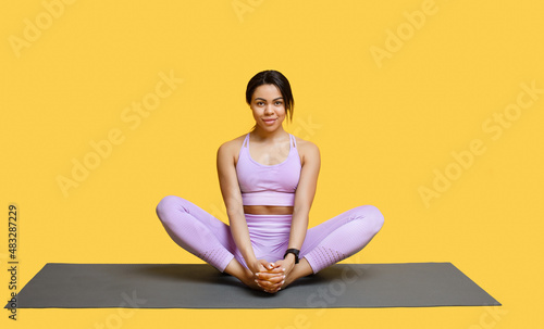 Calm african american woman doing yoga exercise, sitting in baddha konasana, bound angle or butterfly pose © Prostock-studio