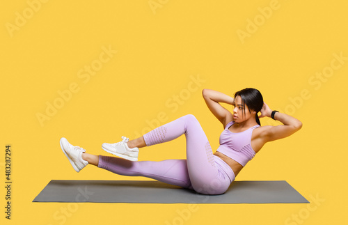 Double crunch excercise. Sporty african american lady working out, doing bicycle crunch abs exercises, yellow background © Prostock-studio