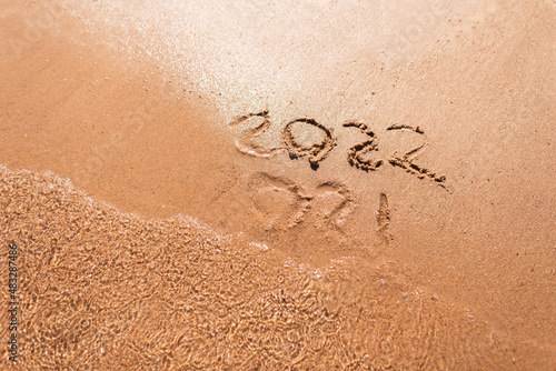 Happy New Year 2022 text on the sea beach. Abstract background photo of coming New Year 2022 and leaving year of 2021