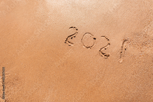 New Year 2021 is written on the beach sand by the sea. Travel season 2021 concept. Summer rest and vacation