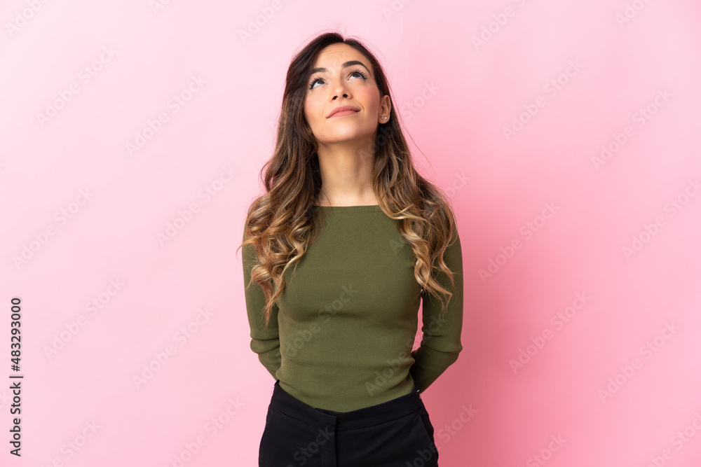 Young caucasian woman isolated on pink background and looking up Young caucasian woman isolated on pink background and looking up
