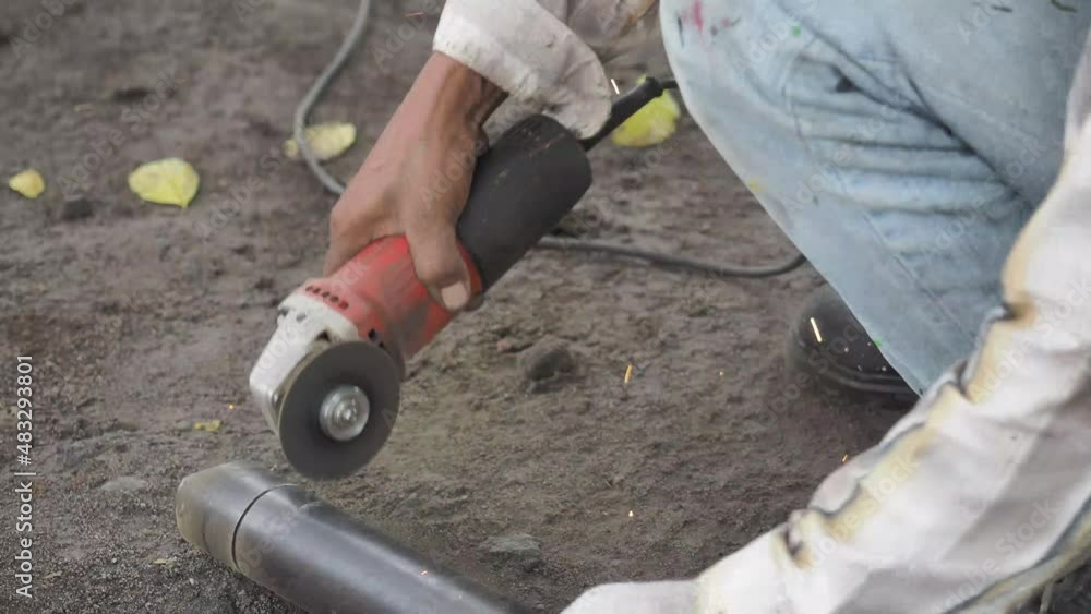 Light sparks when a worker is cutting a metal pipe using a grinder Light sparks when a worker is cutting a metal pipe using a grinder