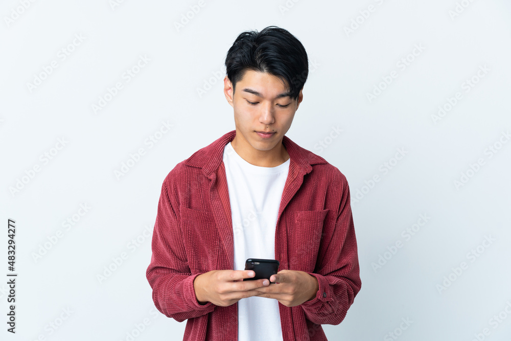 Young Chinese man isolated on white background using mobile phone Young Chinese man isolated on white background using mobile phone