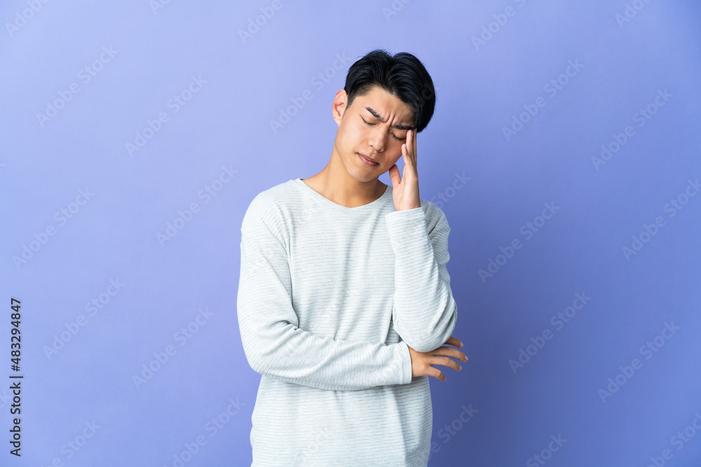 Young Chinese man isolated on purple background with headache Young Chinese man isolated on purple background with headache