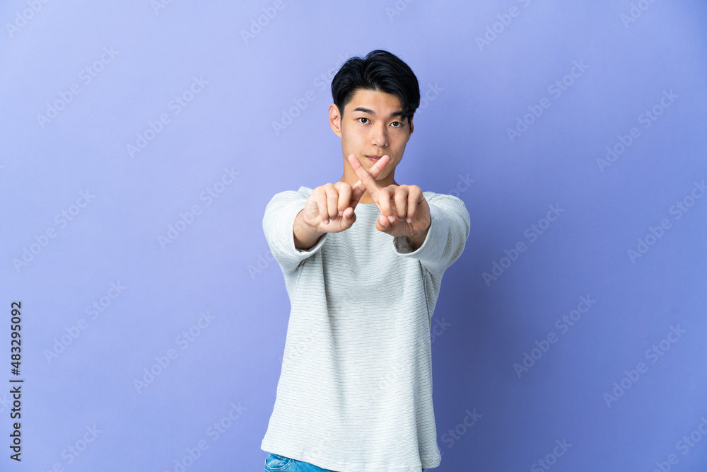 Young Chinese man isolated on purple background making stop gesture with her hand to stop an act Young Chinese man isolated on purple background making stop gesture with her hand to stop an act