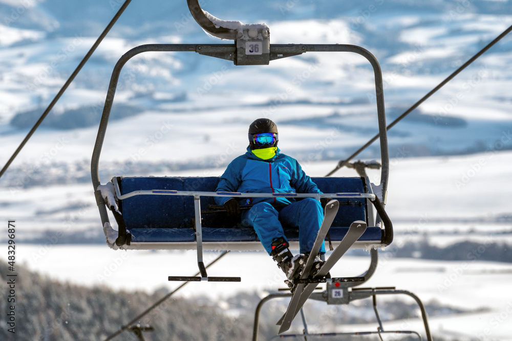 Skier sitting on ski-lift chair or chairlift