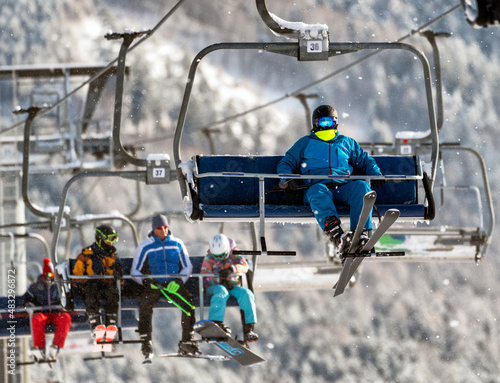 Skier sitting on ski-lift chair or chairlift photo