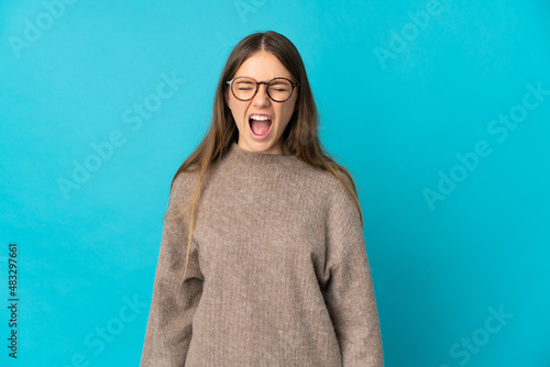 Young Lithuanian woman isolated on blue background shouting to the front with mouth wide open