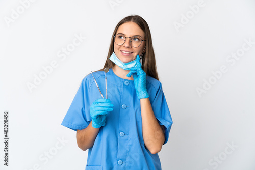 Lithuanian woman dentist holding tools over isolated background thinking an idea while looking up
