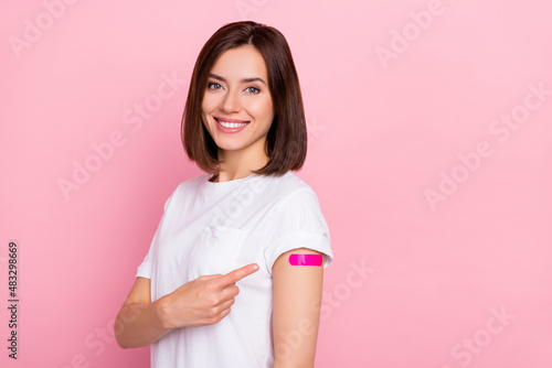 Photo of cheerful lady patient point finger patch on shoulder recommend advert inoculation isolated on pink color background
