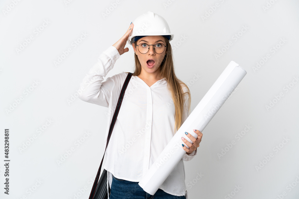 Young Lithuanian architect woman with helmet and holding blueprints isolated on white background with surprise expression Young Lithuanian architect woman with helmet and holding blueprints isolated on white background with surprise expression