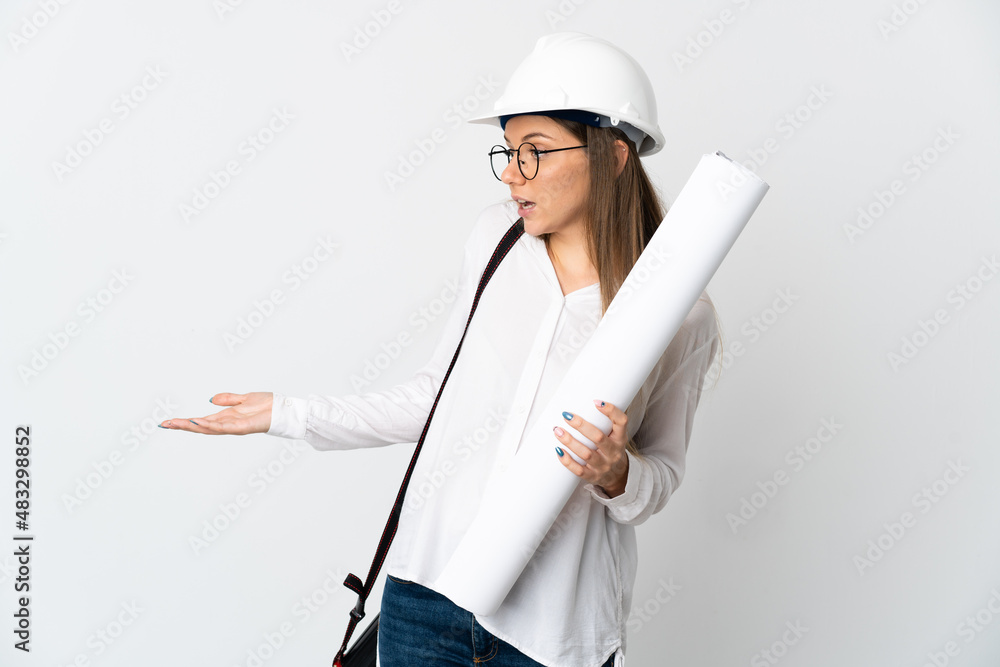 Young Lithuanian architect woman with helmet and holding blueprints isolated on white background with surprise expression while looking side Young Lithuanian architect woman with helmet and holding blueprints isolated on white background with surprise expression while looking side