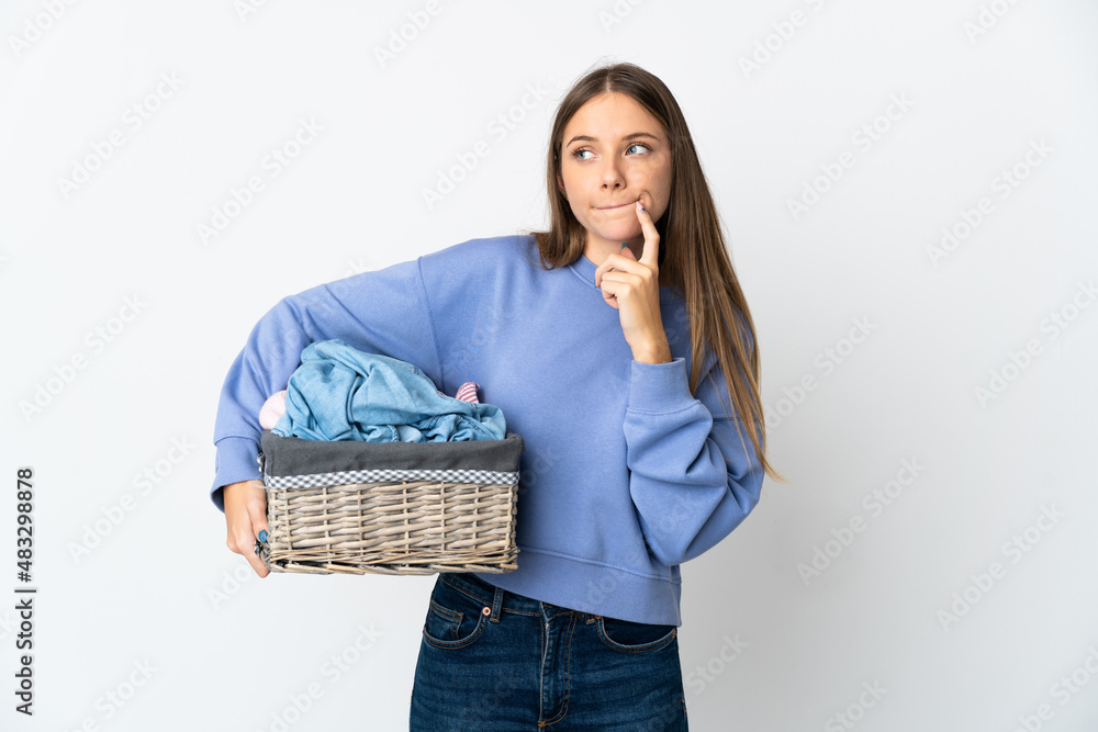 Young Lithuanian woman holding a clothes basket isolated on white background having doubts and thinking Young Lithuanian woman holding a clothes basket isolated on white background having doubts and thinking