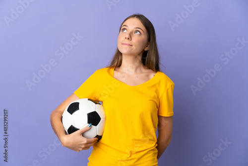 Young Lithuanian football player woman isolated on purple background and looking up © luismolinero