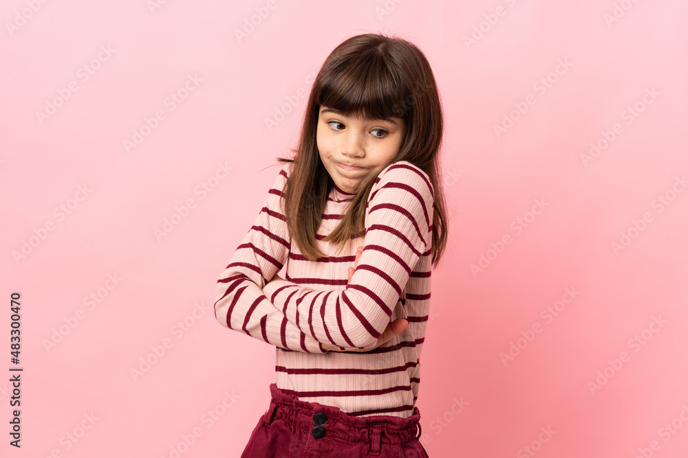 Little girl isolated on pink background making doubts gesture while lifting the shoulders Little girl isolated on pink background making doubts gesture while lifting the shoulders