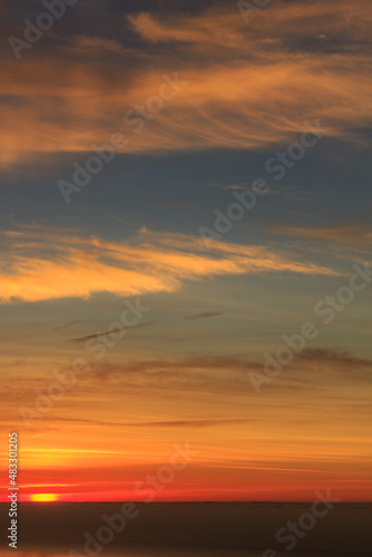 Yellow warm sunrise with sea clouds and ocean in the background. Vertical photo
