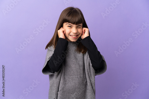 Little girl over isolated background frustrated and covering ears © luismolinero