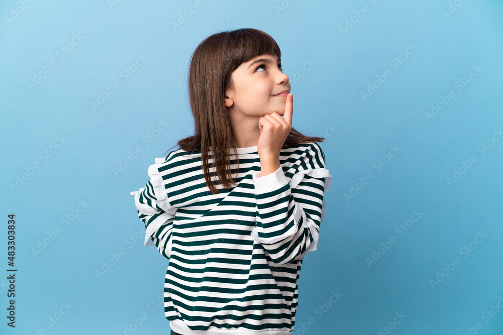Little girl over isolated background having doubts while looking up Little girl over isolated background having doubts while looking up