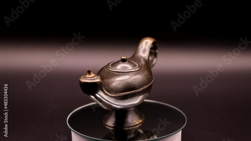 video of an old bronze lamp rotating on a black background
