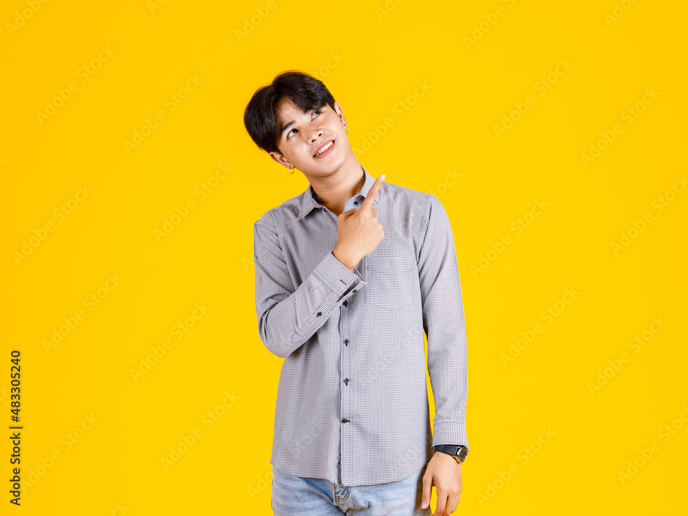 Studio shot of millennial Asian young male fashion model in stylish fashionable casual outfit standing on yellow background Studio shot of millennial Asian young male fashion model in stylish fashionable casual outfit standing on yellow background