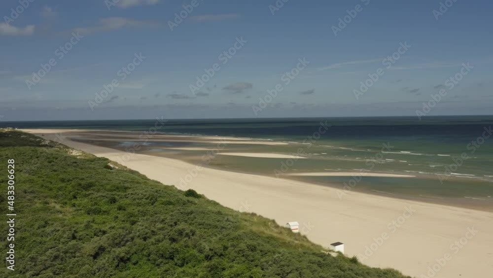 Aerial shot flying over an empty beach towards a beautiful blue sea on a sunny day Aerial shot flying over an empty beach towards a beautiful blue sea on a sunny day