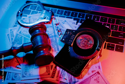 Golden bitcoin with handcuffs and gavel on laptop's keyboard